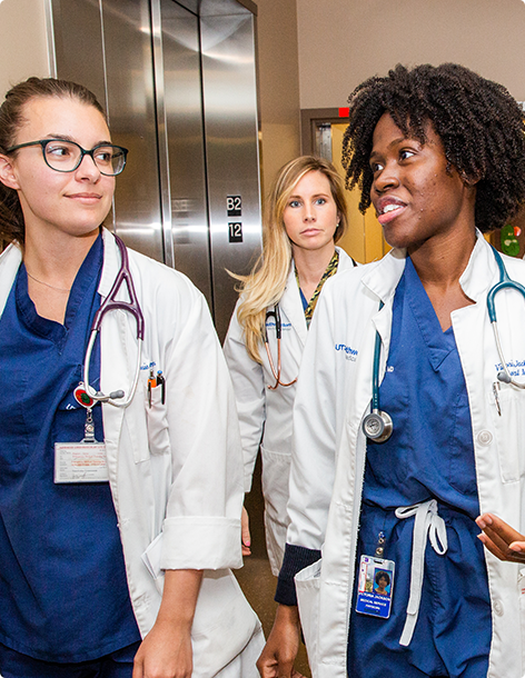 Three doctors walking away from the hospital elevator and talking