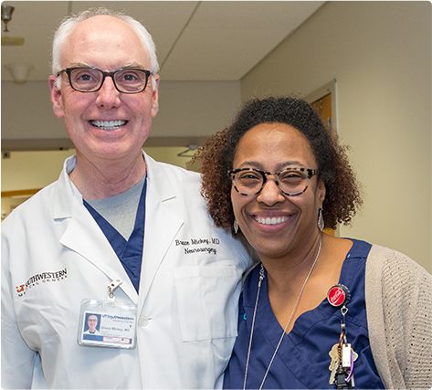 A doctor and nurse standing shoulder to shoulder and smiling