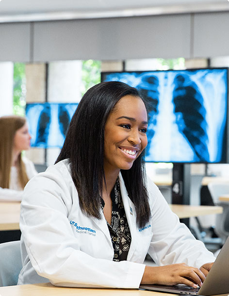 Smiling doctor sits working on her laptop