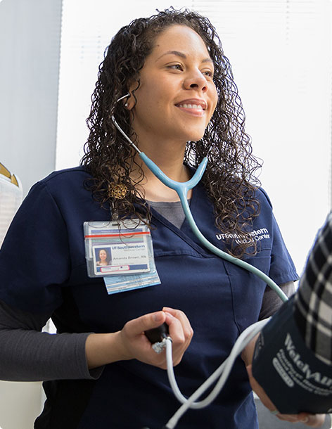 Smiling nurse holding a stethoscope and taking a patient’s blood pressure
