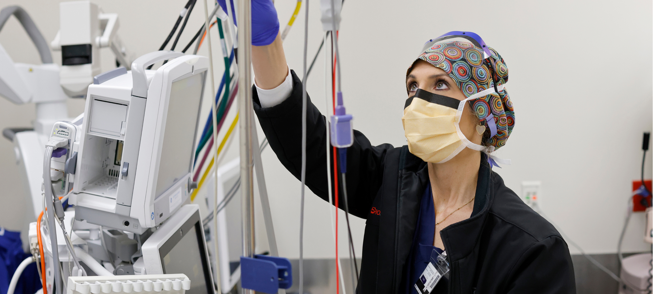 One female certified registered nurse anesthetist (CRNA) looking up and adjusting equipment