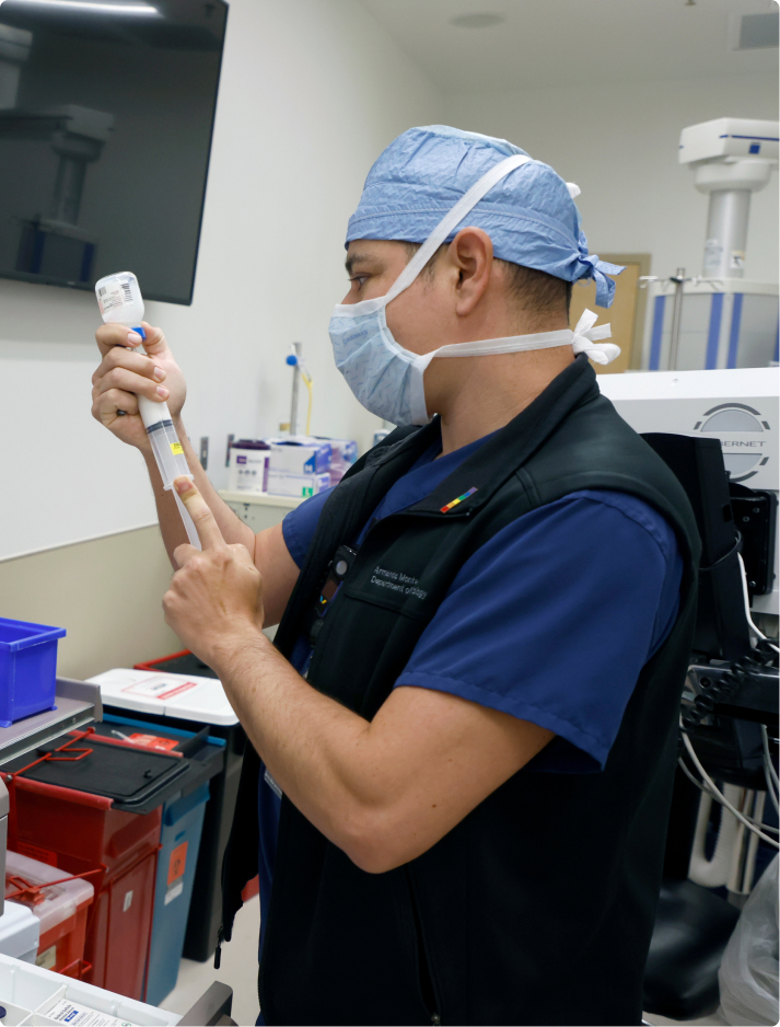 APP_Main_Modality Male advanced practice provider (APP) CRNA with a mask fills syringe